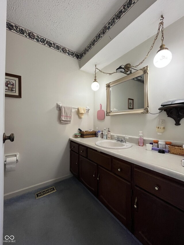 bathroom featuring visible vents, baseboards, a textured ceiling, and vanity