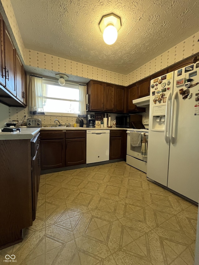 kitchen featuring light floors, white appliances, wallpapered walls, and light countertops