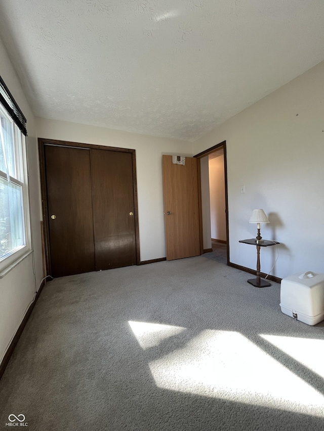 unfurnished bedroom with a closet, baseboards, a textured ceiling, and carpet flooring