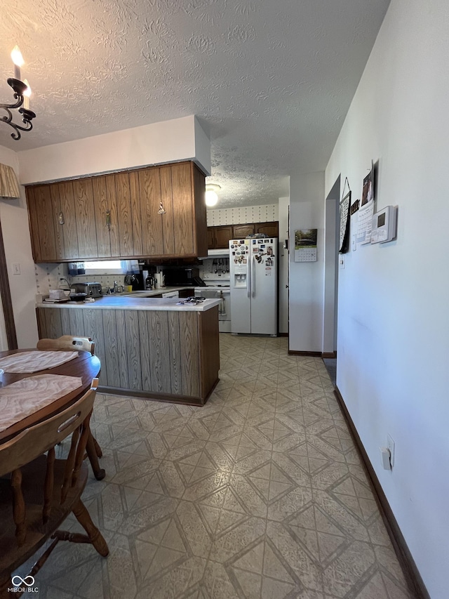 kitchen with tasteful backsplash, white appliances, a peninsula, baseboards, and light floors