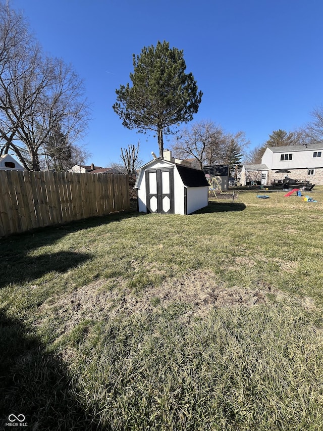 view of yard with an outbuilding, fence, and a shed