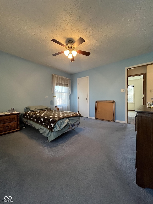 carpeted bedroom featuring baseboards, a textured ceiling, and ceiling fan