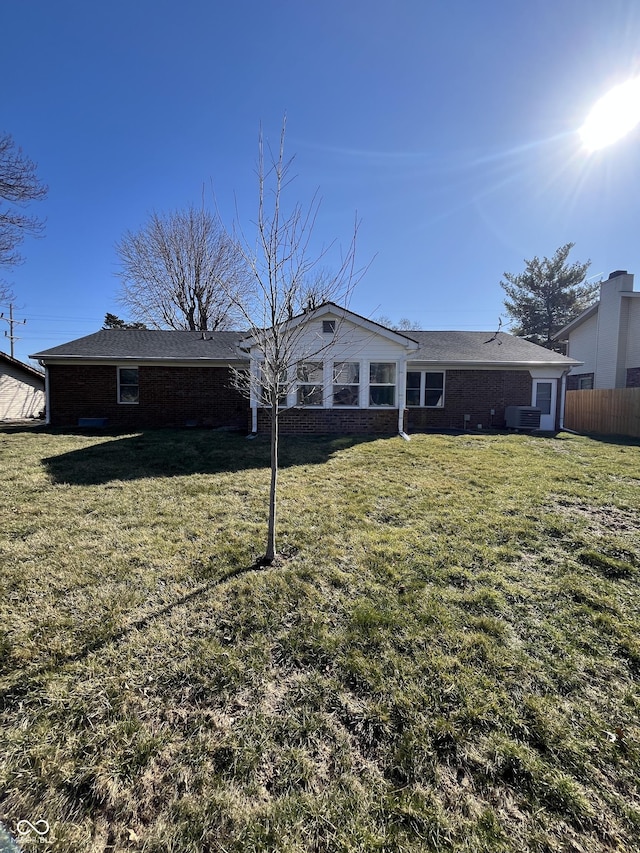 rear view of property featuring brick siding, a lawn, cooling unit, and fence