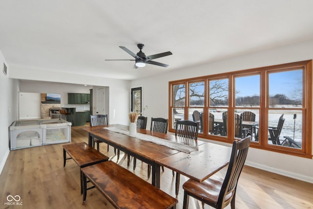 dining space with visible vents, baseboards, light wood finished floors, and ceiling fan