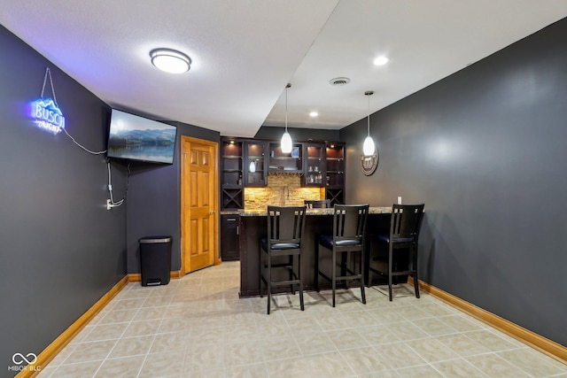 bar featuring visible vents, wet bar, backsplash, and baseboards