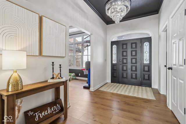 entrance foyer featuring crown molding, wood finished floors, baseboards, and a chandelier