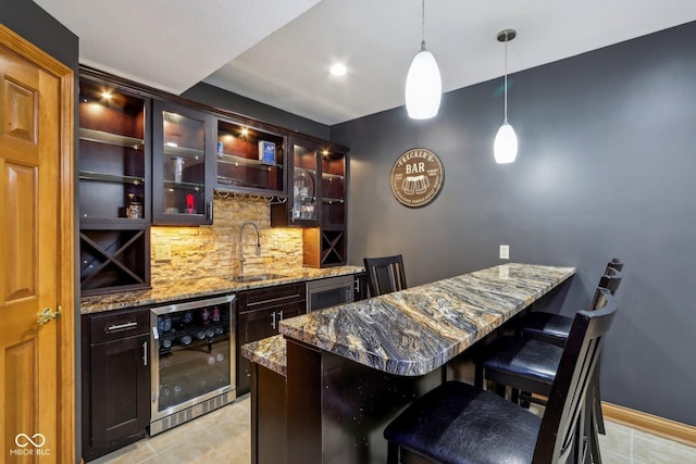 bar featuring a sink, decorative light fixtures, light tile patterned flooring, indoor wet bar, and decorative backsplash