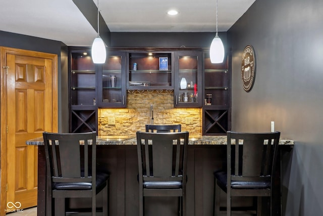 bar with hanging light fixtures, decorative backsplash, and wet bar