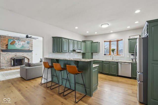 kitchen featuring a sink, a kitchen bar, appliances with stainless steel finishes, and green cabinets