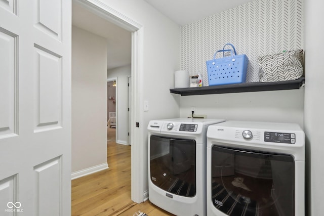 clothes washing area featuring baseboards, light wood-style floors, laundry area, and washing machine and clothes dryer