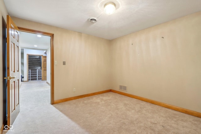 spare room featuring baseboards, visible vents, and light carpet