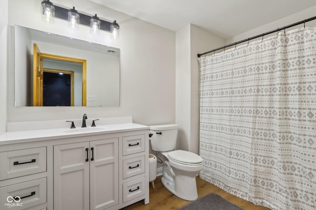 bathroom with a shower with shower curtain, toilet, vanity, and wood finished floors