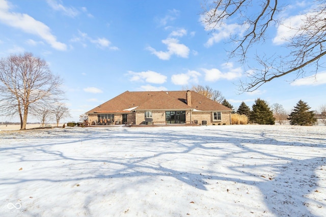 snow covered back of property with brick siding