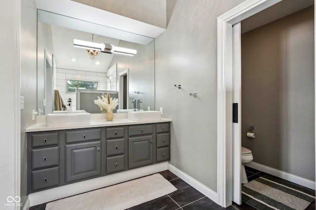 bathroom with a notable chandelier, toilet, a sink, double vanity, and baseboards