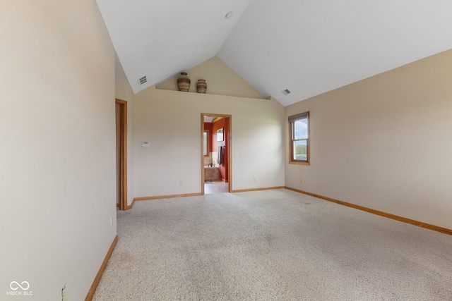 unfurnished room with light colored carpet, baseboards, and high vaulted ceiling
