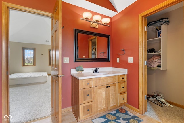 bathroom featuring baseboards, visible vents, lofted ceiling, and vanity