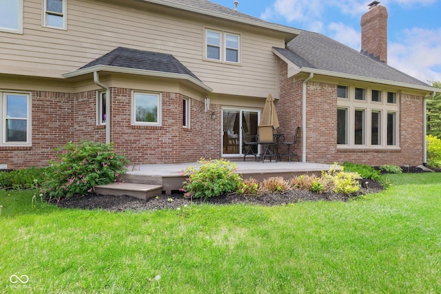 back of house with a lawn, a chimney, a shingled roof, and brick siding