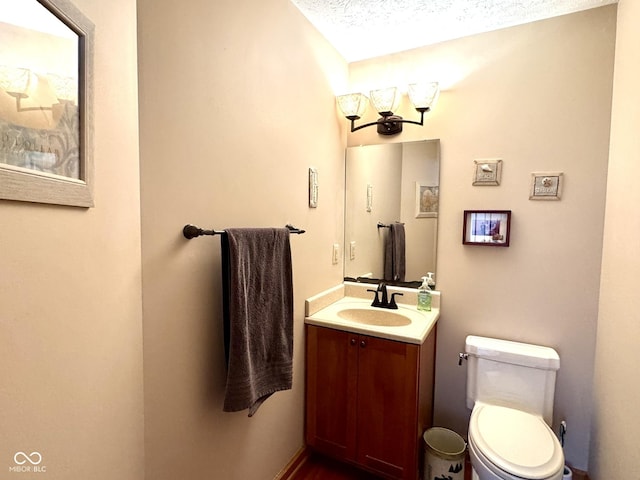 half bath with vanity, a textured ceiling, and toilet