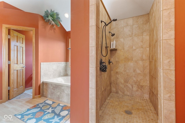bathroom featuring tiled shower and a bath