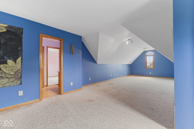 additional living space featuring baseboards, carpet, and vaulted ceiling