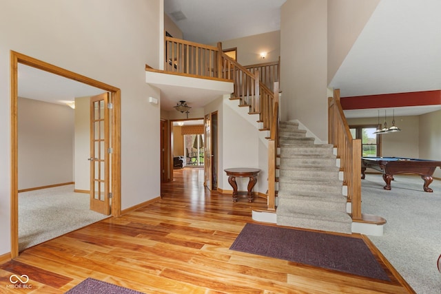 stairway with baseboards, a towering ceiling, wood finished floors, and pool table