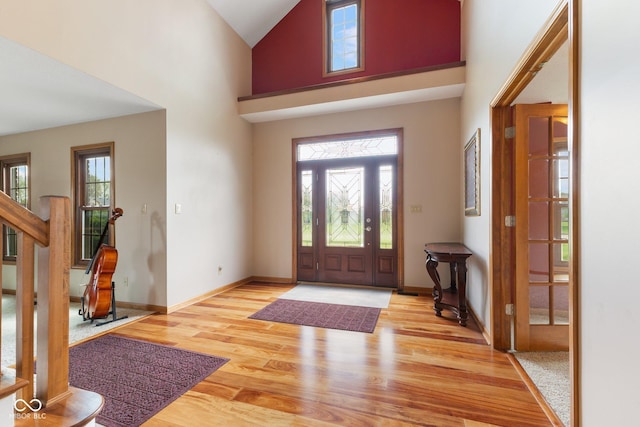 entrance foyer featuring light wood-type flooring, baseboards, stairs, and a high ceiling