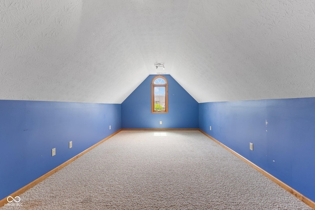 additional living space featuring baseboards, carpet flooring, a textured ceiling, and lofted ceiling