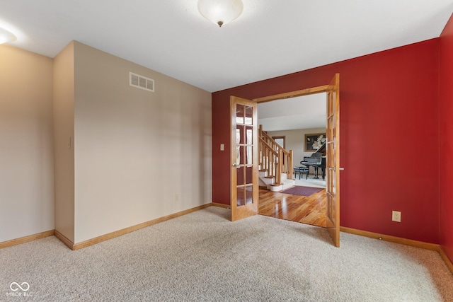 unfurnished room featuring visible vents, stairs, carpet floors, and baseboards