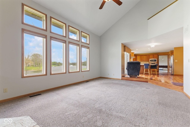 unfurnished living room with light colored carpet, baseboards, and a wealth of natural light