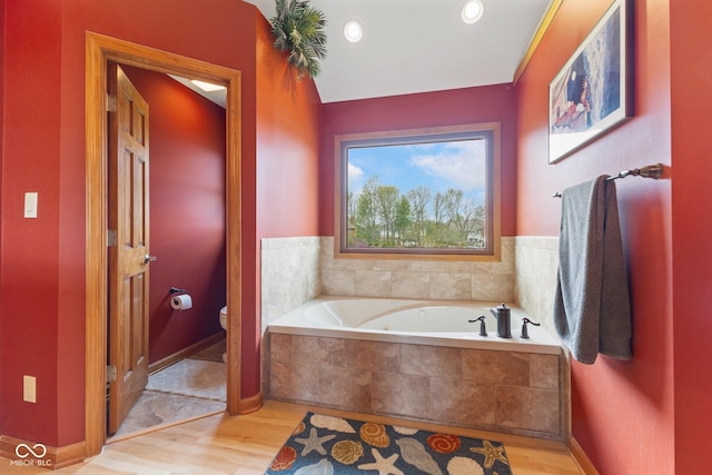 bathroom featuring recessed lighting, a bath, wood finished floors, and toilet