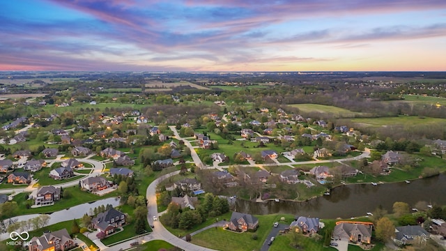 aerial view at dusk featuring a water view and a residential view