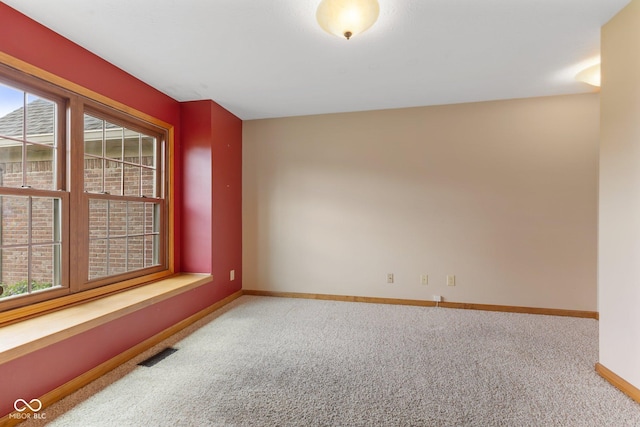 empty room with baseboards, visible vents, and carpet