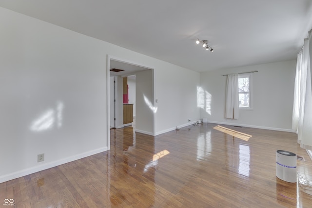 spare room featuring visible vents, baseboards, and wood finished floors