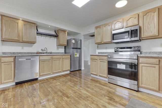 kitchen featuring appliances with stainless steel finishes, light wood-style flooring, and light brown cabinets