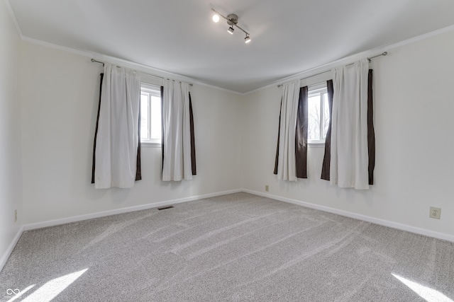 unfurnished room featuring crown molding, carpet, baseboards, and a wealth of natural light