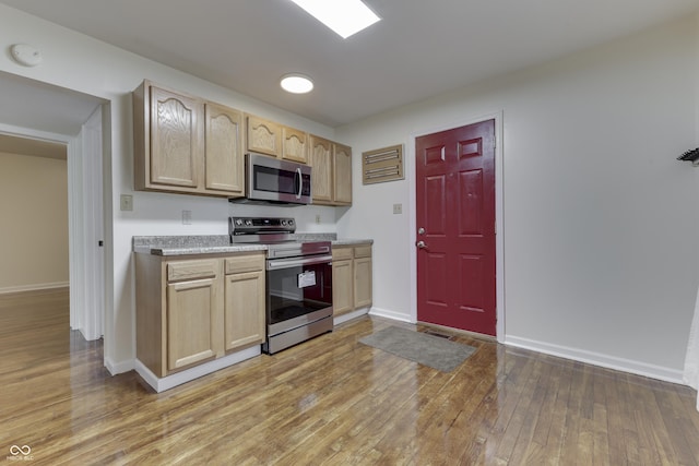 kitchen with stainless steel appliances, light countertops, light brown cabinets, and light wood finished floors