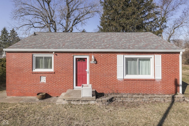 bungalow-style home featuring brick siding and roof with shingles