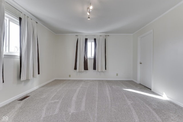 spare room with light carpet, visible vents, baseboards, and ornamental molding