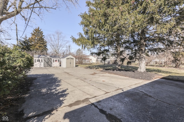 view of yard with concrete driveway, a storage shed, and an outdoor structure