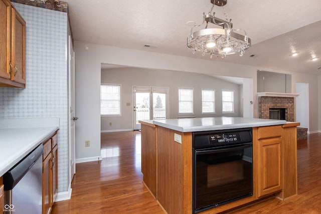 kitchen with wood finished floors, visible vents, dishwasher, black oven, and open floor plan