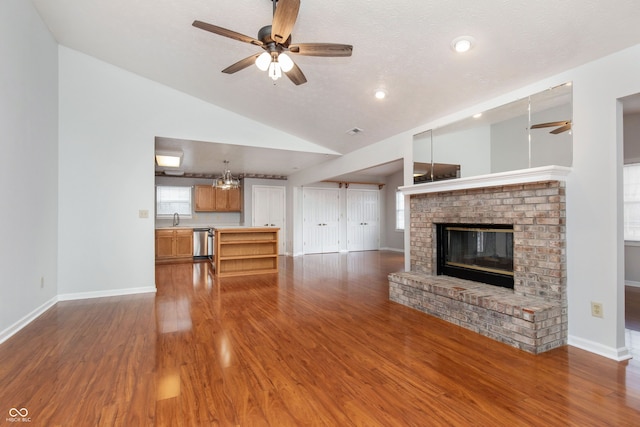 unfurnished living room featuring wood finished floors, a brick fireplace, a ceiling fan, and a sink