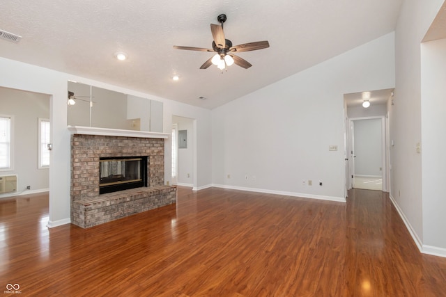 unfurnished living room with visible vents, a brick fireplace, vaulted ceiling, wood finished floors, and a ceiling fan