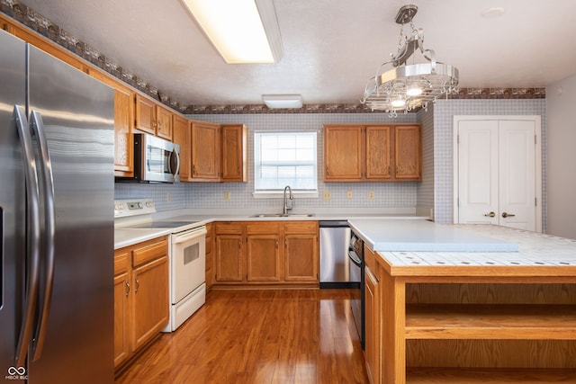 kitchen with brown cabinetry, wood finished floors, open shelves, a sink, and stainless steel appliances