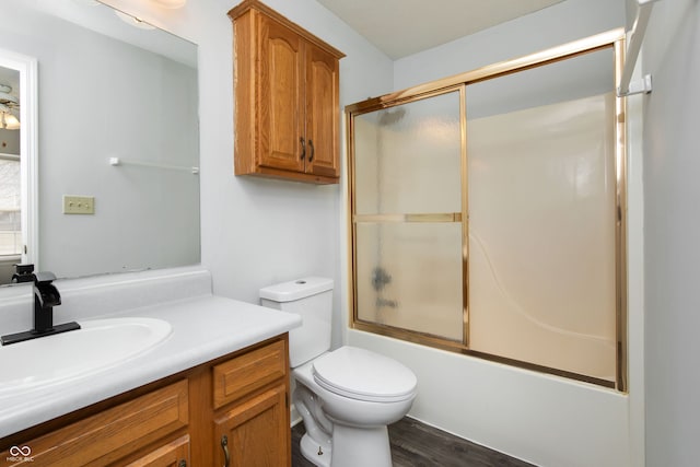 bathroom featuring shower / bath combination with glass door, wood finished floors, vanity, and toilet