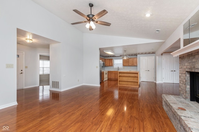 unfurnished living room featuring visible vents, dark wood-type flooring, ceiling fan, vaulted ceiling, and a fireplace