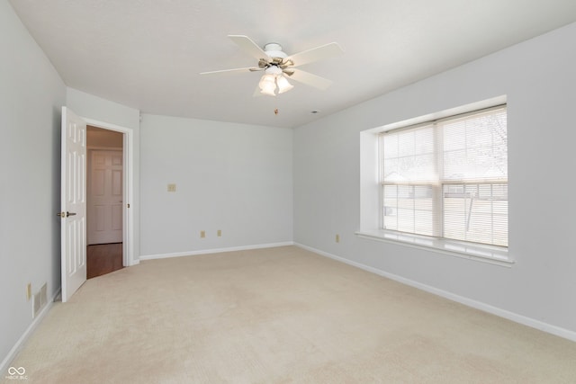 empty room featuring light colored carpet, visible vents, and baseboards