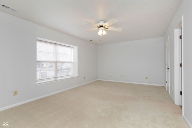 spare room with baseboards, light colored carpet, visible vents, and ceiling fan