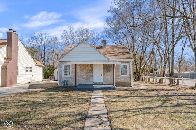 bungalow-style home with a front lawn, fence, covered porch, and stone siding