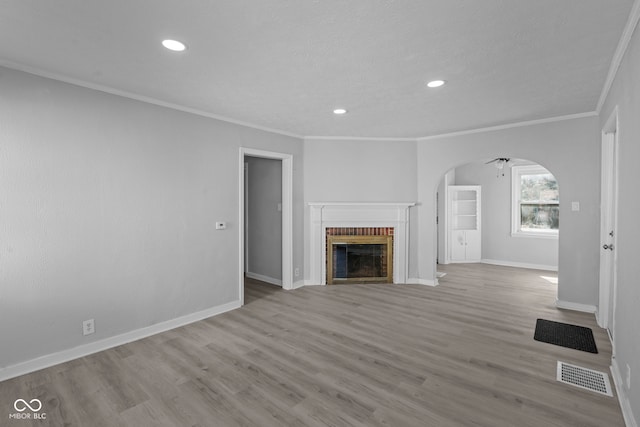 unfurnished living room featuring a brick fireplace, arched walkways, visible vents, and baseboards