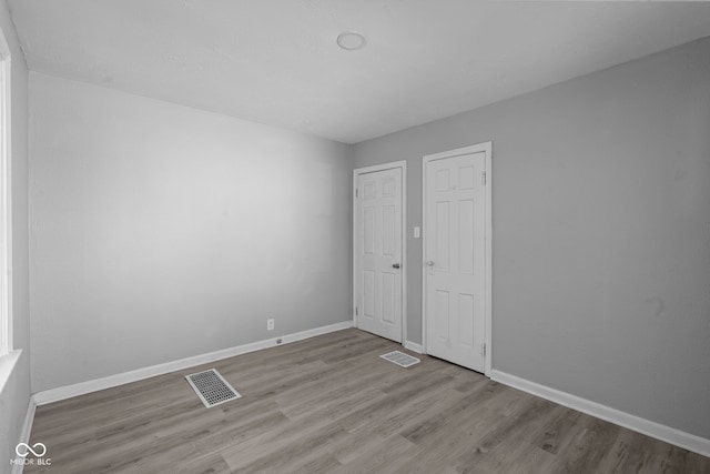 unfurnished room with wood finished floors, baseboards, and visible vents